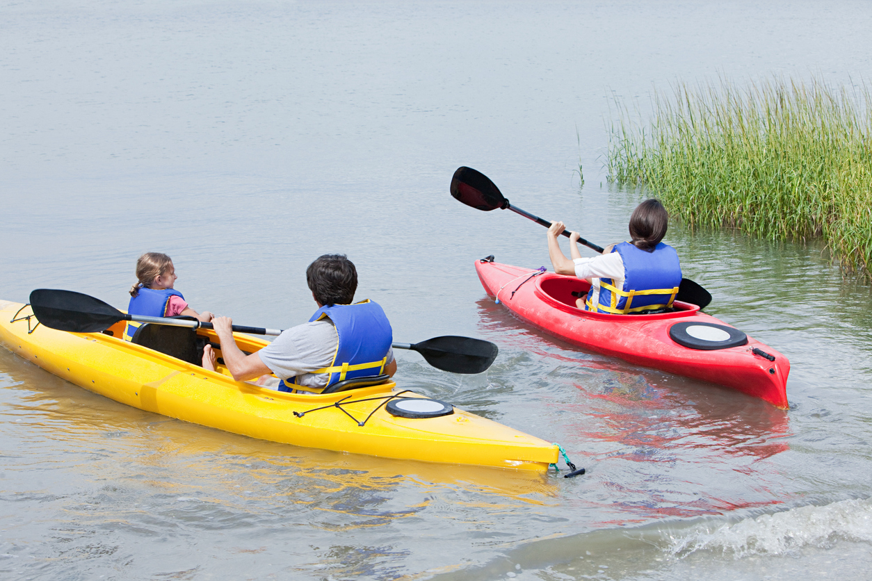 chiropractic care for summer sports, People canoeing on a river wearing helmets and life vests