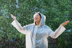 Beat the Winter Blues: How Chiropractic Care for Winter Pain Relief Boosts Mood and Mobility, Rainy day asian woman wearing a raincoat outdoors. She is happy.