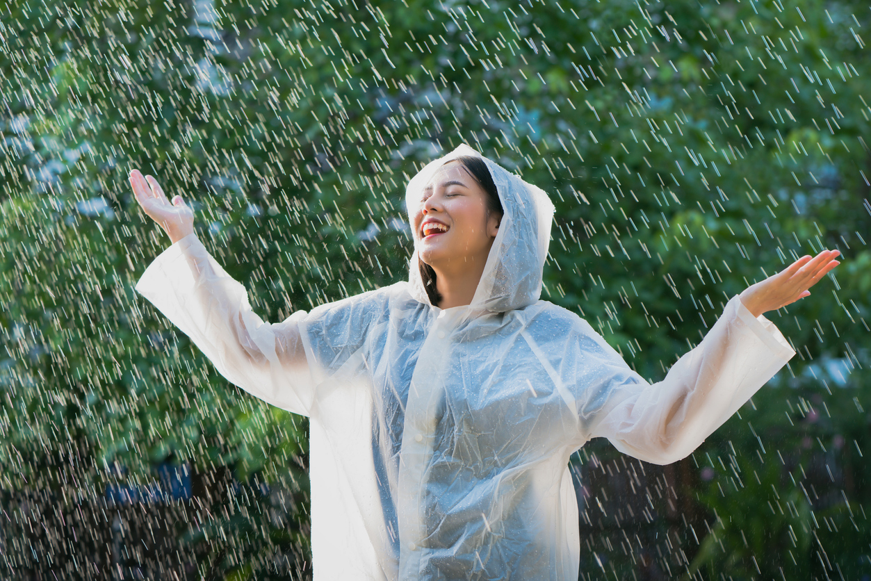 Beat the Winter Blues: How Chiropractic Care for Winter Pain Relief Boosts Mood and Mobility, Rainy day asian woman wearing a raincoat outdoors. She is happy.