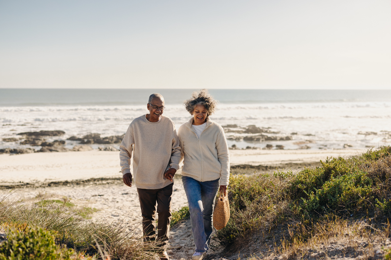 Thankful for Relief: How Chiropractic Care Restores Comfort and Mobility in Little River, SC, Cheerful elderly couple smiling happily while walking away from the beach after a picnic. Romantic senior couple enjoying a seaside getaway after retirement.