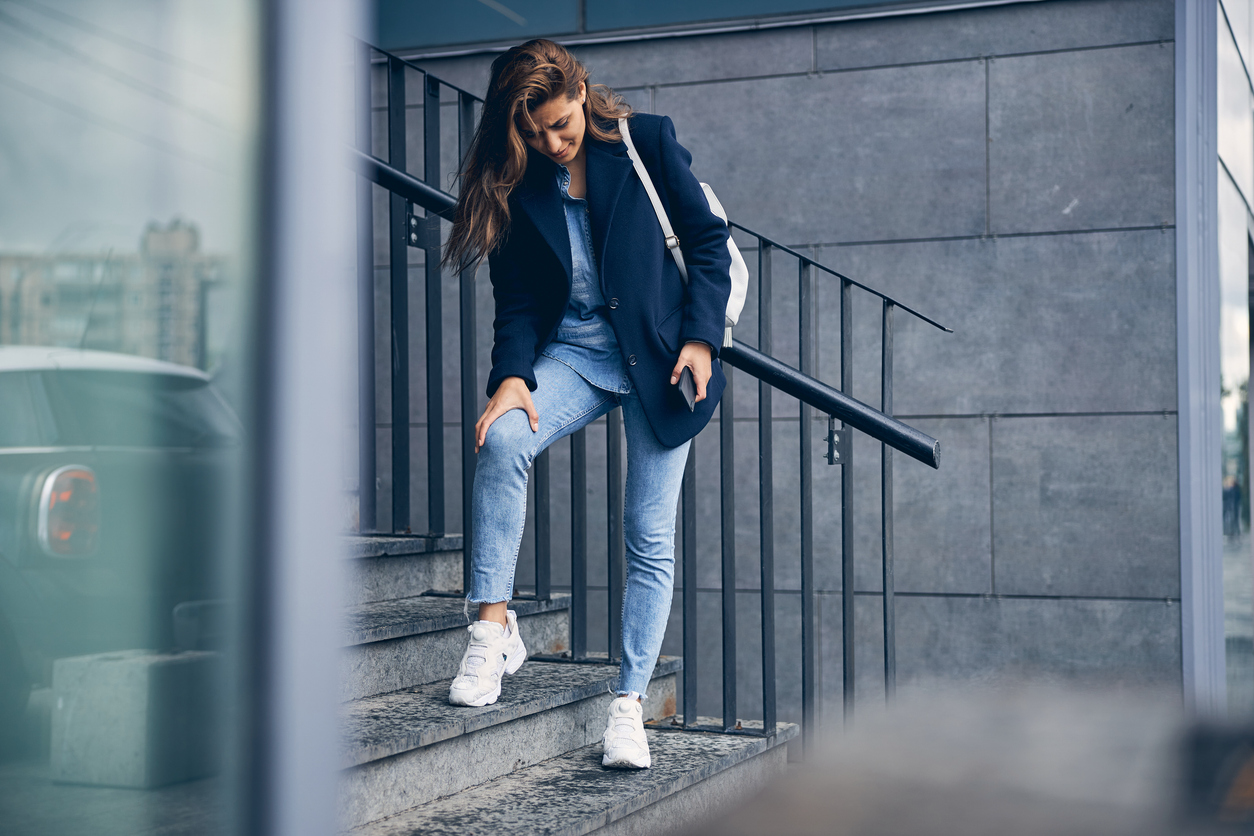 Woman experiencing knee pain while using the stairs