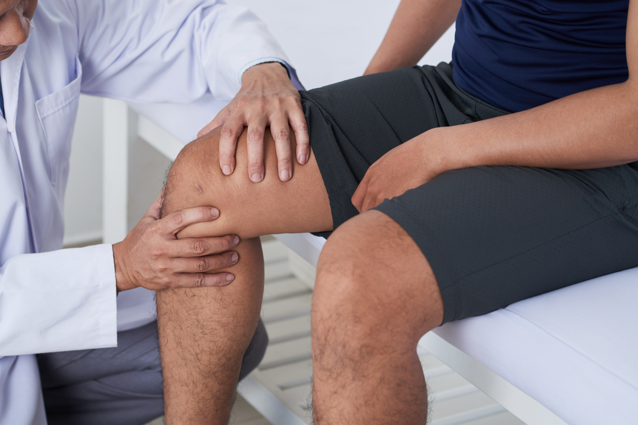 Doctor examining a patient’s knee for pain and joint function.