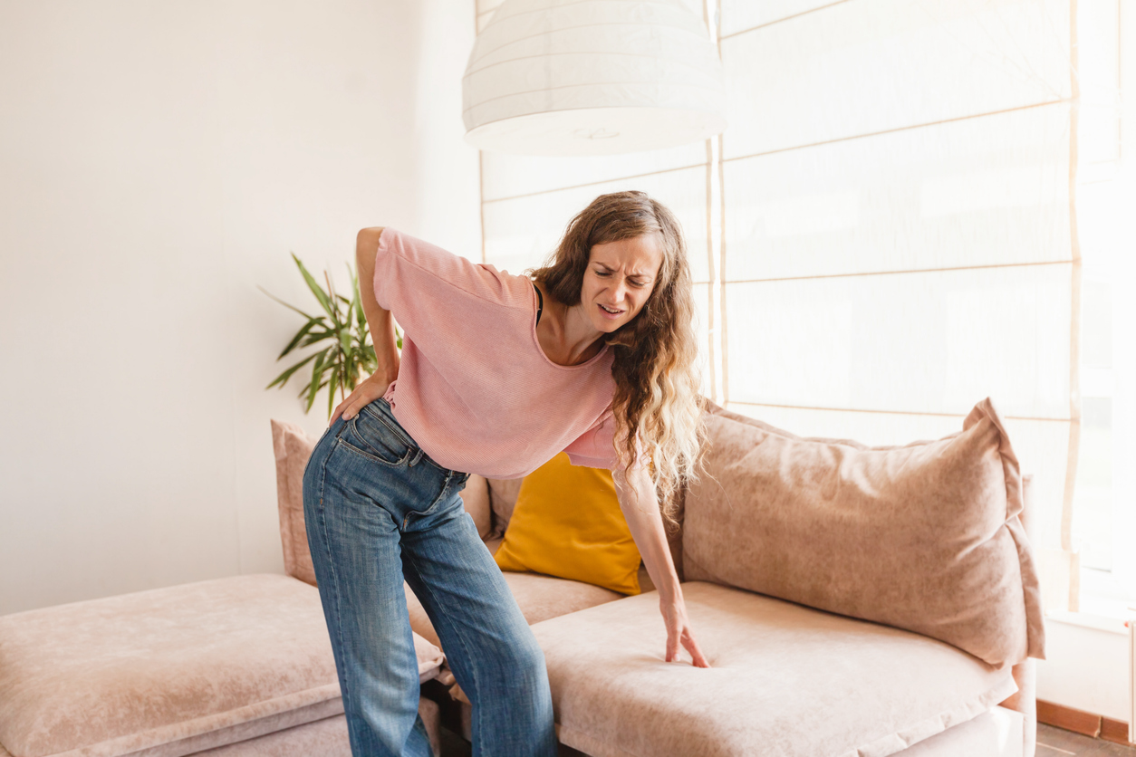 Young woman experiencing back pain when standing up after sitting